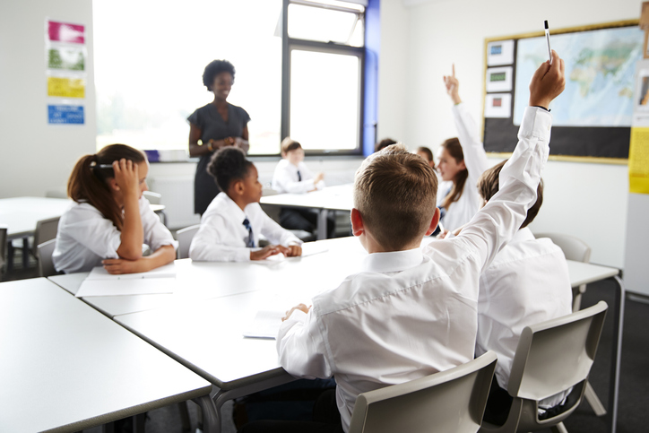 Pupil raising hand in primary school classroom